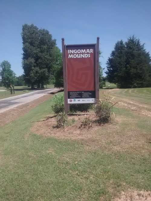 Sign for Ingomar Mounds, surrounded by grass and trees, with a clear blue sky in the background.