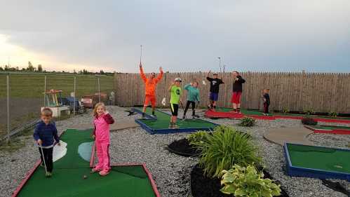 A group of children and teens celebrate on a mini-golf course, with colorful outfits and playful poses.