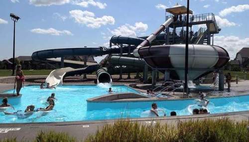 A water park featuring multiple slides and a pool with people enjoying the attractions under a sunny sky.