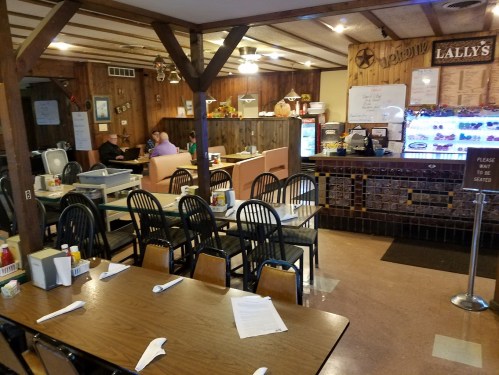 A cozy diner interior with wooden decor, tables set for dining, and a counter displaying menus and condiments.