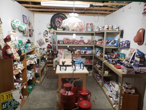 A cluttered vintage shop filled with collectibles, toys, and memorabilia on shelves and tables.