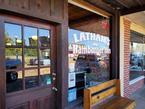 A wooden door with glass panes leads to Latham's Hamburger Inn, featuring a sign in the window and a bench outside.