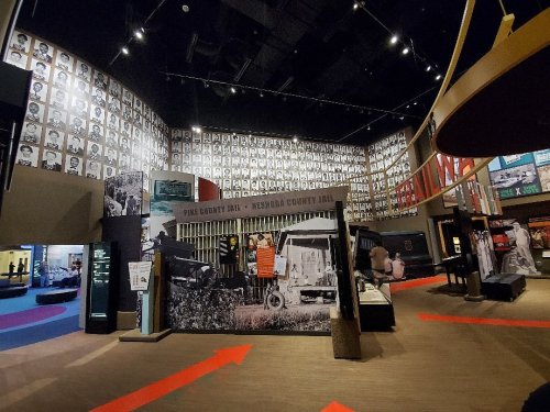 Interior of a museum exhibit featuring historical photos and displays about jails, with arrows guiding visitors.
