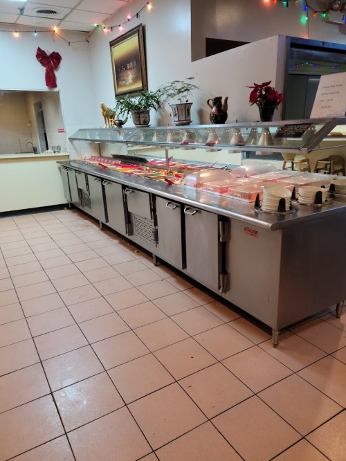 A buffet setup with a long metal counter displaying various food items, surrounded by festive decorations.