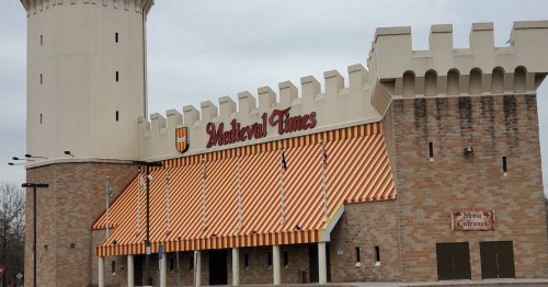Exterior of Medieval Times building featuring a castle-like design and striped awnings.