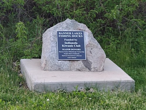 A stone monument with a plaque recognizing the Indianola Kiwanis Club for funding fishing docks at Banner Lakes.