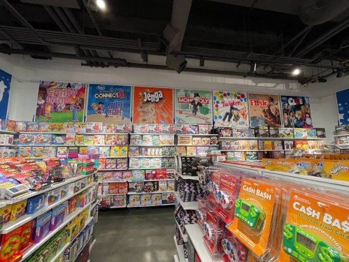 A colorful toy store aisle filled with board games and toys, featuring popular titles like Jenga and Monopoly on display.