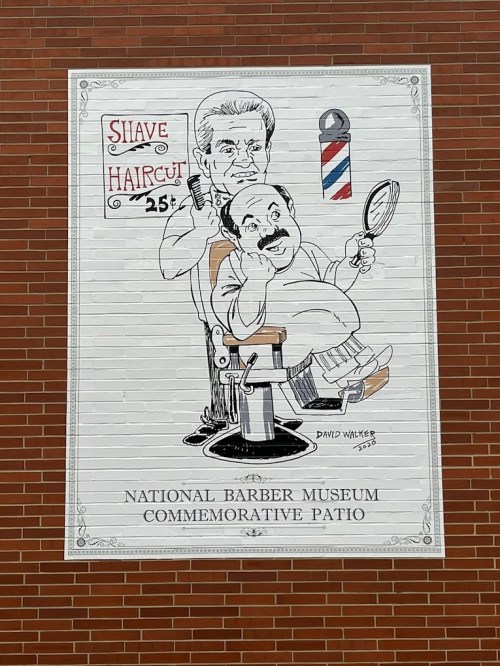 A mural depicting a barber giving a haircut, with a sign reading "Shave Haircut 25¢" and "National Barber Museum."