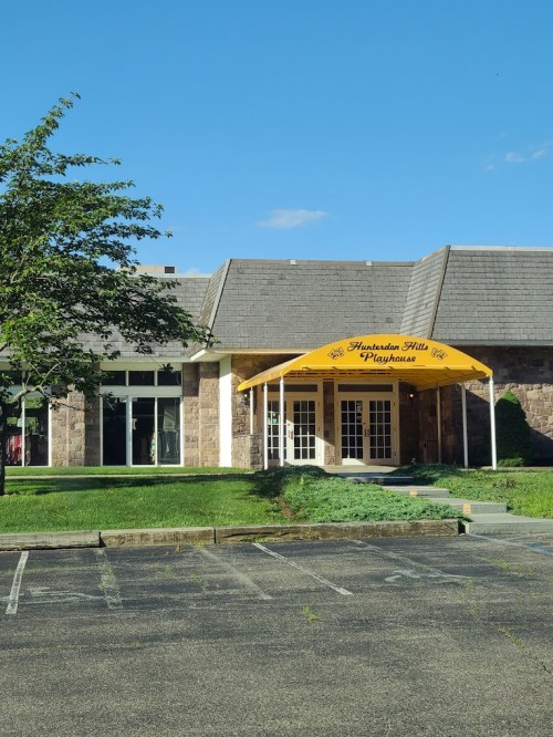 A building with a yellow awning labeled "Shenandoah Hills Playhouse" and a clear blue sky above.