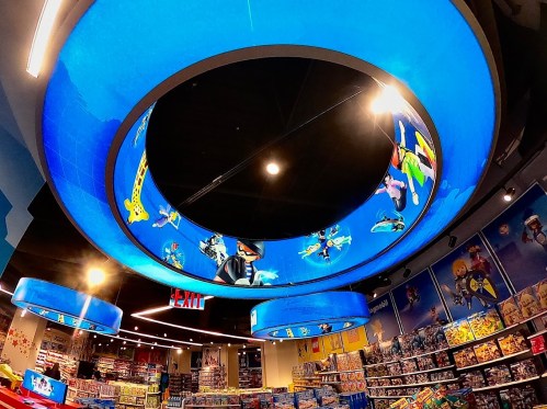 Colorful circular ceiling display in a toy store, featuring animated characters and a bright blue background.