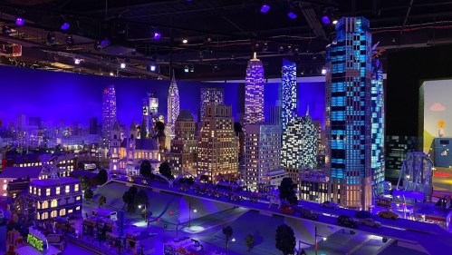A vibrant miniature cityscape with illuminated skyscrapers and detailed buildings, set against a colorful backdrop.