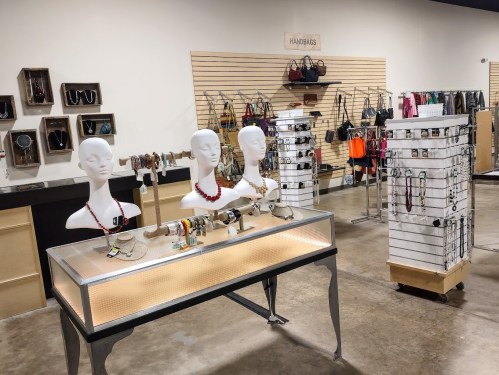 A retail display featuring jewelry on mannequins, handbags on racks, and accessories in a well-lit store.