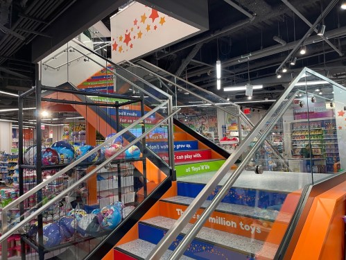 Interior of a colorful toy store featuring stairs, shelves of toys, and vibrant decorations.