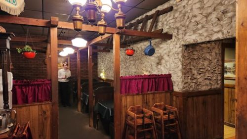 Cozy restaurant interior with wooden decor, hanging lights, and a server in the background.