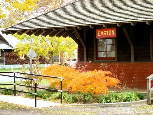 Historic train station with a sign reading "EASTON," surrounded by colorful autumn foliage and a ramp.