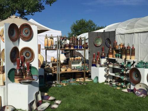 A vibrant outdoor market display featuring various pottery pieces, including plates, bowls, and decorative bottles.