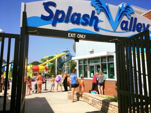 Entrance to Splash Valley water park with colorful slides in the background and visitors exiting.