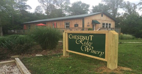 A wooden winery building with a sign reading "Chestnut Ridge Winery" surrounded by greenery and trees.