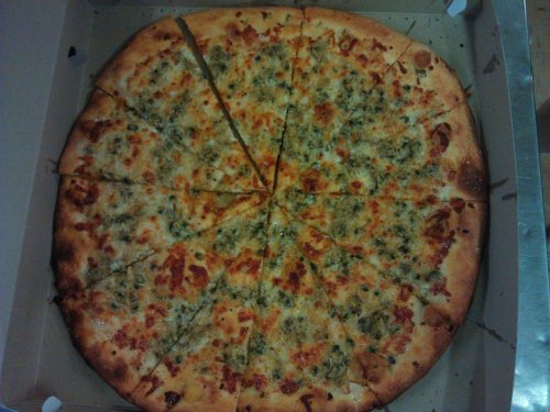 A large pizza with a golden crust, topped with melted cheese and herbs, cut into slices in a pizza box.