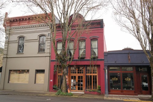 Colorful historic buildings with large windows and trees lining the street, creating a charming urban scene.