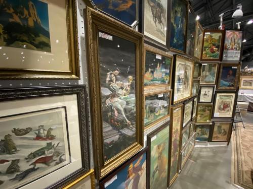 A gallery wall filled with various framed artworks, including paintings and prints in different styles and sizes.