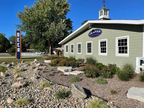 A green building with a sign reading "BEER" and a landscaped garden featuring rocks and flowers under a clear blue sky.