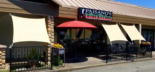 Exterior of Paisano's Italian Kitchen, featuring a sign, outdoor seating, and awnings on a sunny day.