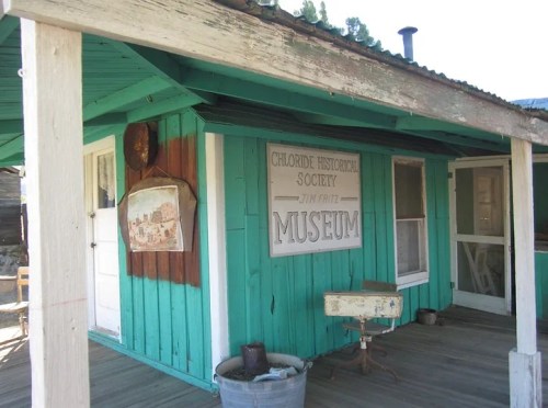 A turquoise building with a sign reading "Museum" and a historical society plaque on the wall.