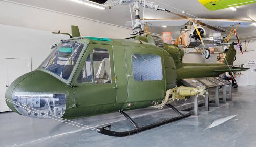 A green military helicopter displayed in a museum, showcasing its cockpit and rotor system.