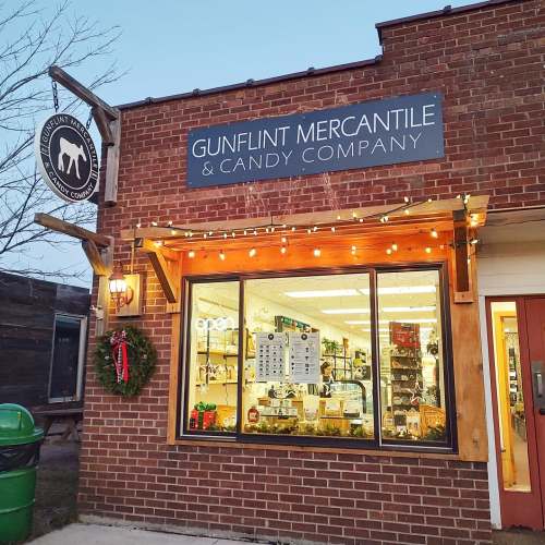 Exterior of Gunflint Mercantile & Candy Company, featuring a festive sign, lights, and a wreath on the door.