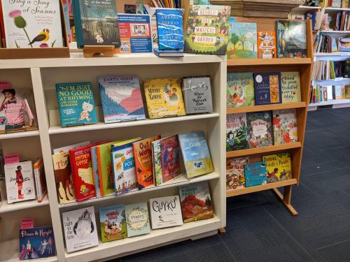 A cozy bookstore display featuring colorful children's books on shelves and a wooden stand.