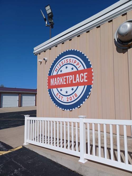 Sign on a building featuring "Mississippi Marketplace" with an established date of 2018, against a clear blue sky.