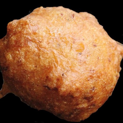 A close-up of a golden-brown, round fried snack with a crispy texture against a black background.