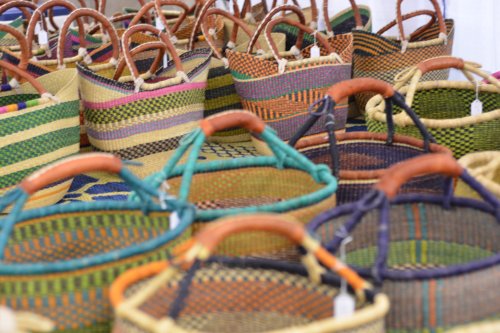 A variety of colorful woven baskets with wooden handles displayed together.