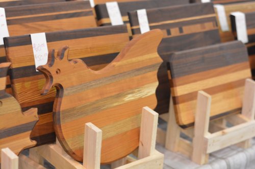 A display of wooden cutting boards in various shapes and colors, including a chicken-shaped board.
