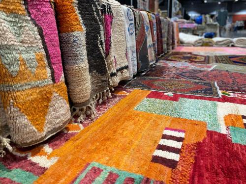 Colorful, patterned rugs stacked and displayed in a market setting, showcasing intricate designs and textures.