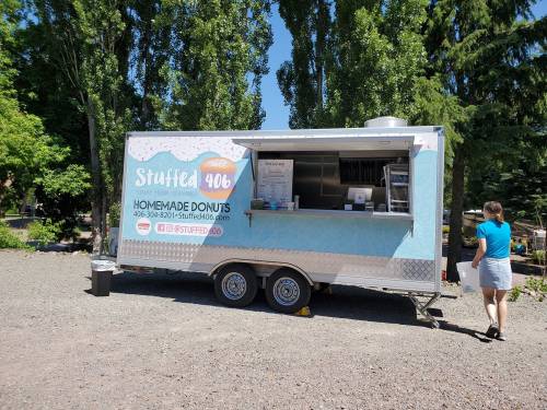 A food truck named "Stuffed 406" offers homemade donuts, set in a green outdoor area with trees.