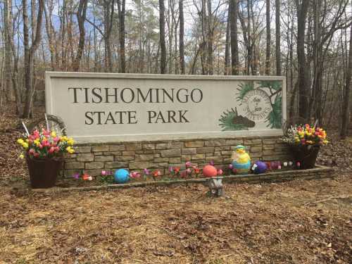 Sign for Tishomingo State Park surrounded by colorful flowers and Easter decorations in a wooded area.