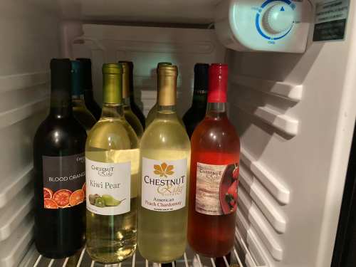 A refrigerator filled with various bottles of wine, including red and white varieties, neatly arranged on the shelves.