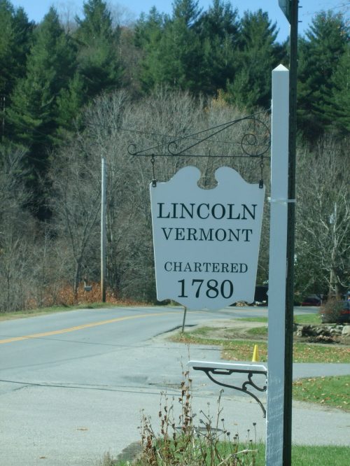 Sign for Lincoln, Vermont, chartered in 1780, displayed along a rural road with trees in the background.