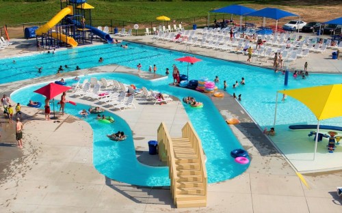A vibrant water park scene with pools, slides, and families enjoying the sun on colorful floats and lounge chairs.
