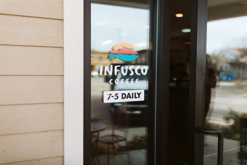 Sign on a glass door displaying "Infusco Coffee" and hours: 7-5 Daily.
