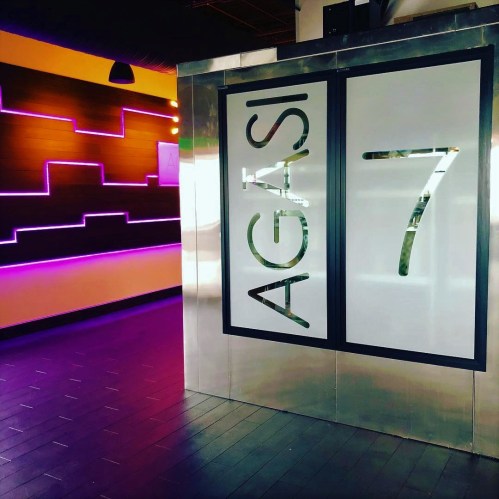 Modern interior featuring a sleek entrance with "AGASI 7" sign and colorful illuminated wall design.