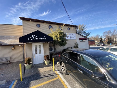 Exterior of Steve's restaurant with a black awning, parked car, and clear blue sky in the background.