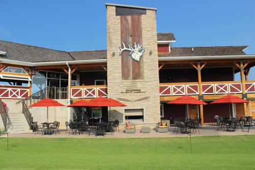 A rustic building with a stone facade, featuring red umbrellas over outdoor seating and a large moose emblem.