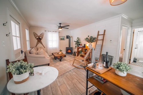 Cozy living room with a beige sofa, wooden ladder, plants, and a fireplace, featuring warm lighting and a welcoming atmosphere.