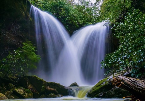 A serene waterfall cascading over rocks, surrounded by lush greenery and mist, creating a tranquil natural scene.