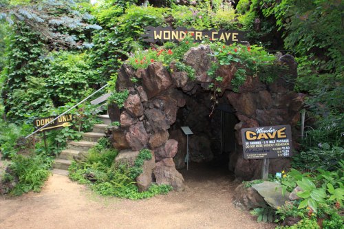 Entrance to Wonder Cave, surrounded by lush greenery and stone steps, with signs indicating "Down Only."