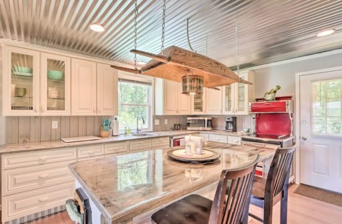 Bright kitchen with a large island, wooden accents, and a unique hanging light fixture, featuring modern appliances.