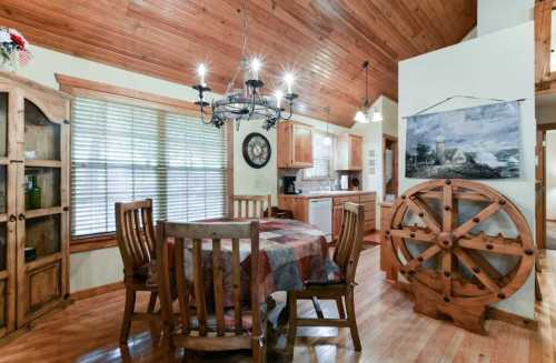 Cozy dining area with wooden furniture, a chandelier, and a decorative wheel on the wall, featuring warm wood accents.